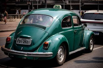 Táxi verde circula por uma rua movimentada de São Paulo.