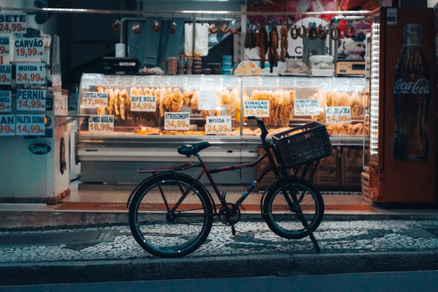Bicicleta estacionada diante de uma loja iluminada em Curitiba, com produtos expostos na vitrine.